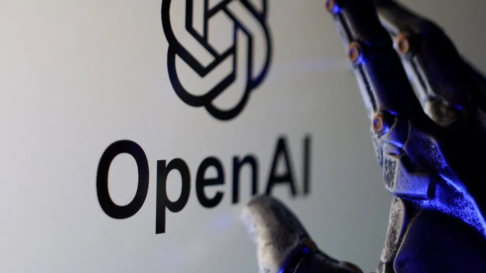 A robotic hand positioned next to the OpenAI logo on a screen highlights the ongoing debate surrounding artificial intelligence advances.